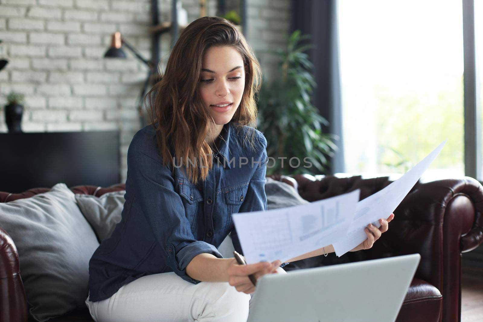 Business woman checking paper documents in home office,working on laptop from home