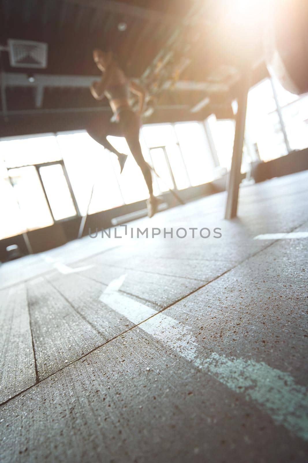 Sport training concept. Vertical shot of athletic woman in sportswear working out at industrial gym, focus on the floor by friendsstock