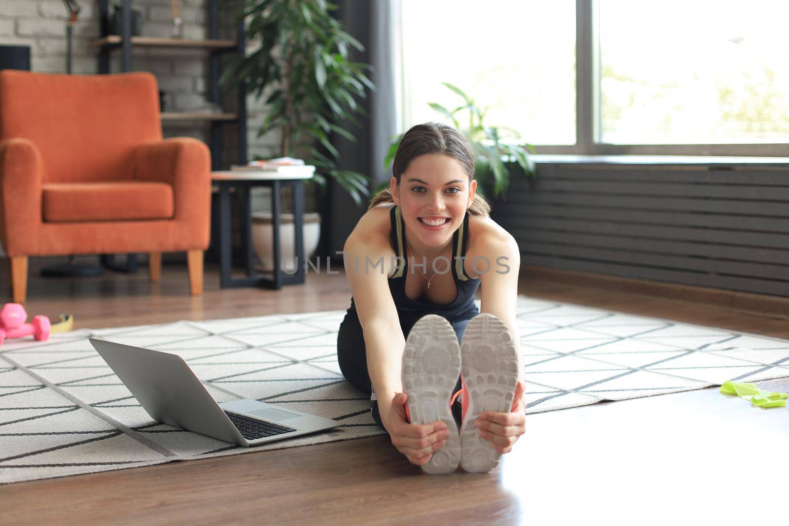 Fitness beautiful slim woman doing fitness stretching exercises at home in the living room. Stay at home activities. Sport, healthy lifestyle. by tsyhun