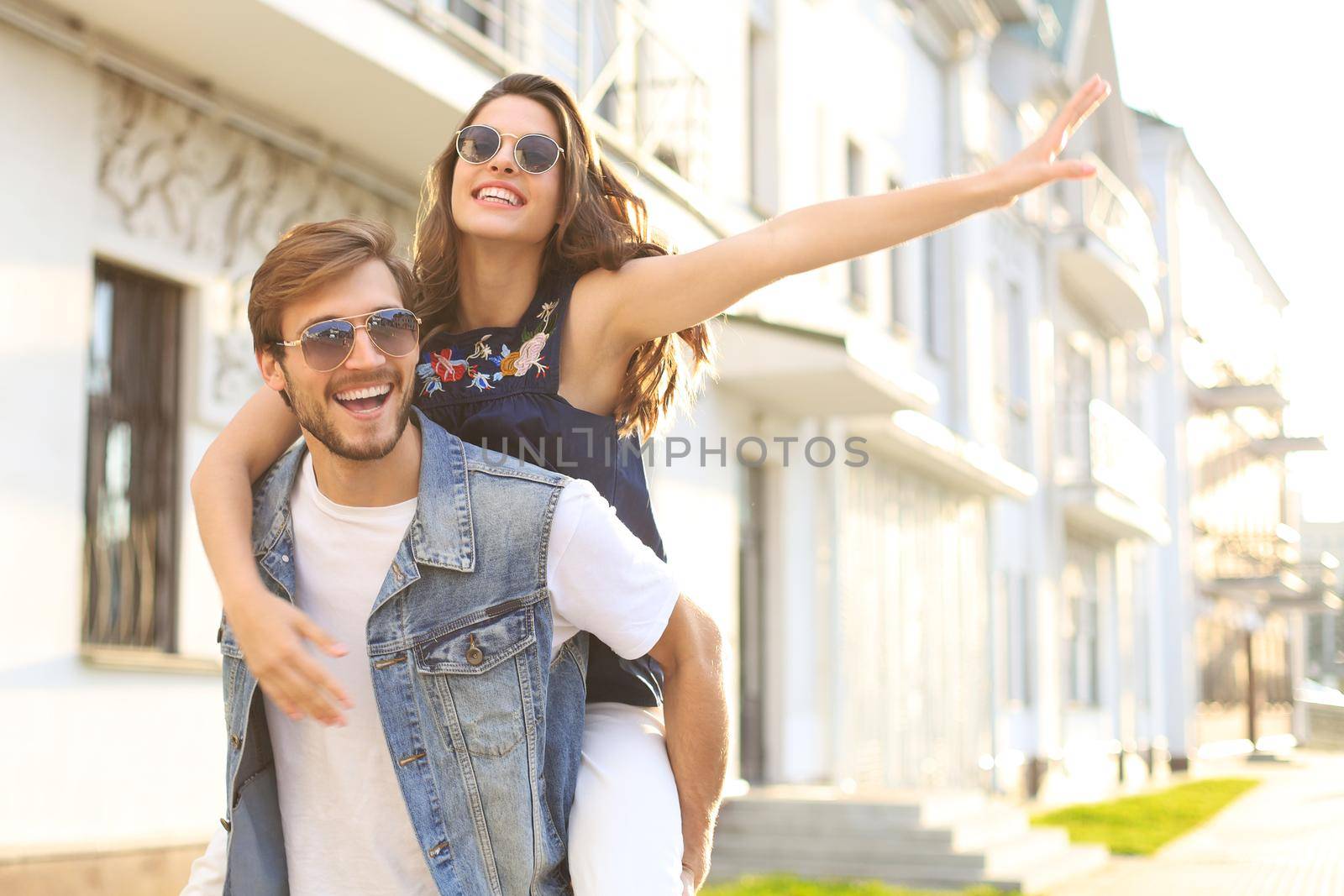 Handsome young man carrying young attractive woman on shoulders while spending time together outdoors