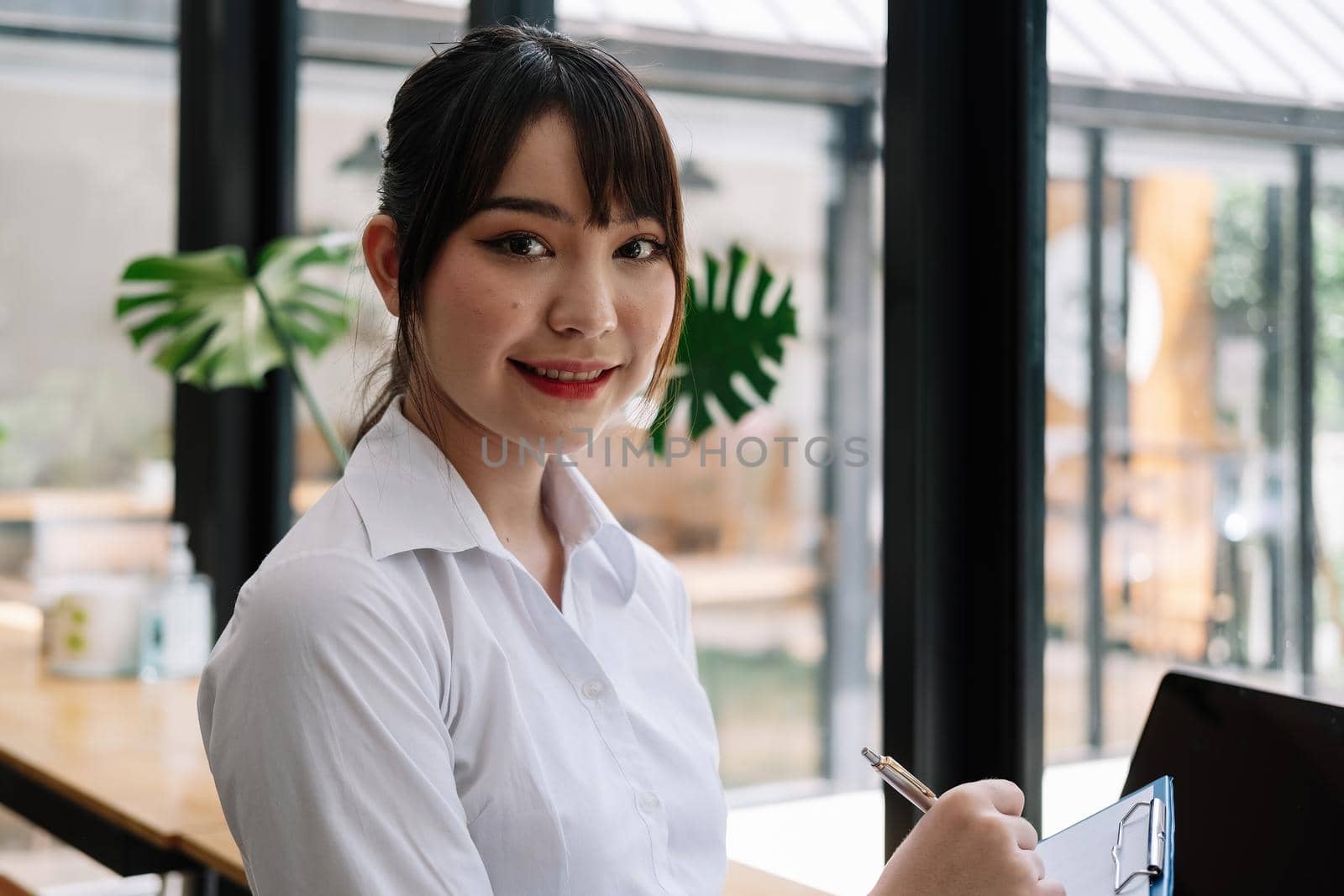 A portrait of an Asian university student during taking note on notepad.