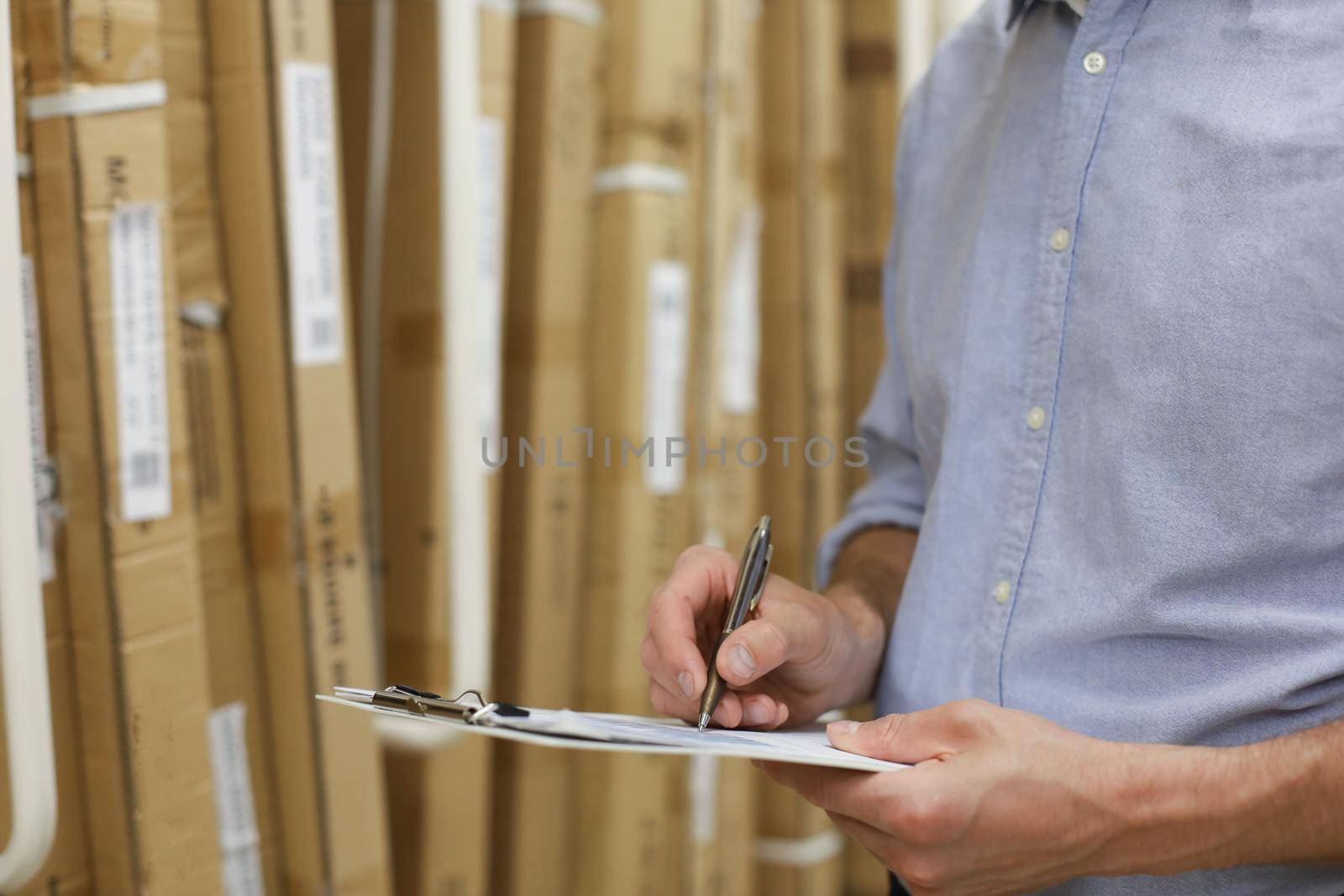 Young man shopping or working in a hardware warehouse standing checking supplies on his tablet. by tsyhun