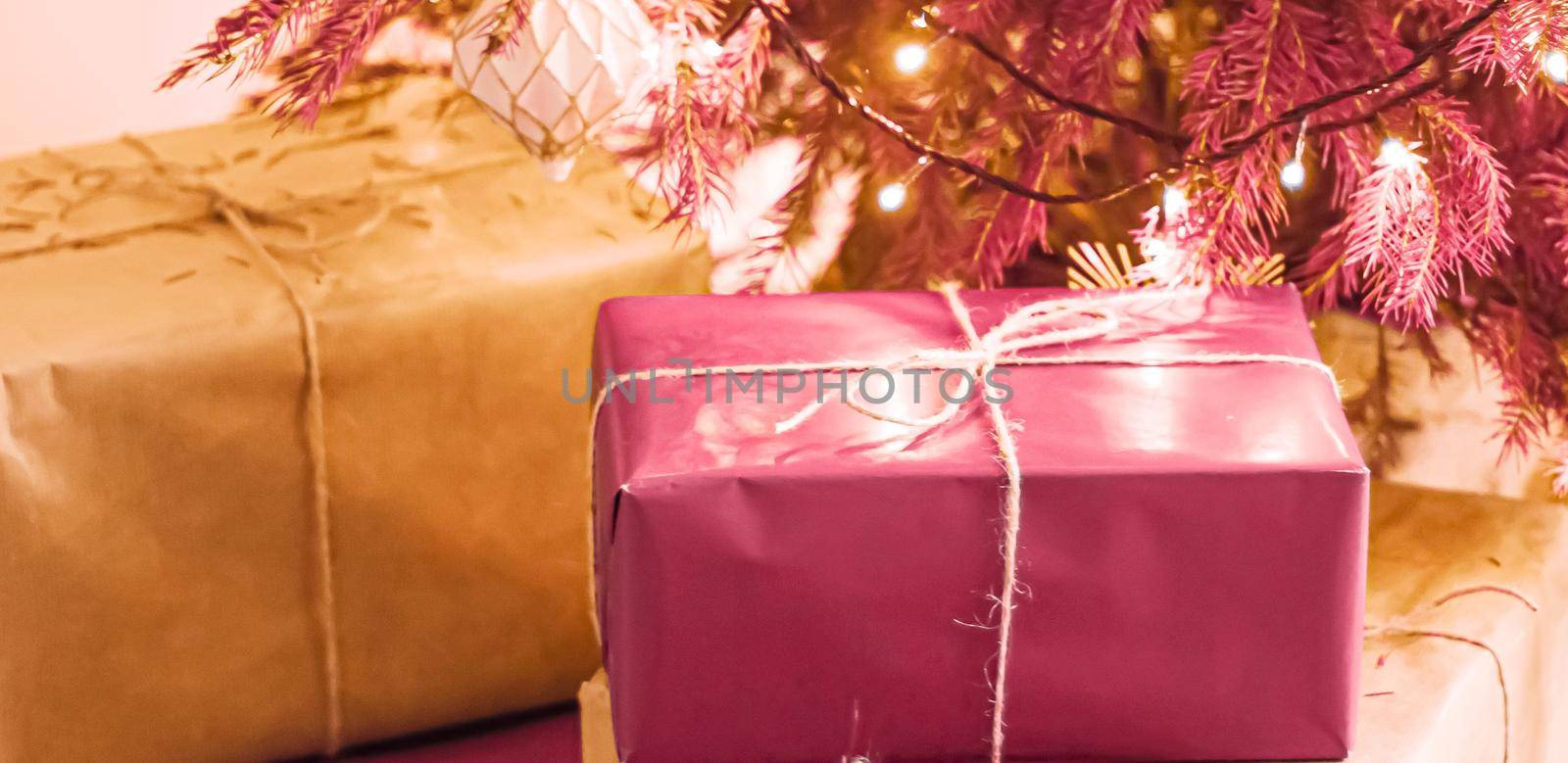 Christmas holiday delivery and sustainable gifts concept. Pink gift boxes wrapped in eco-friendly packaging with recycled paper under decorated xmas tree.