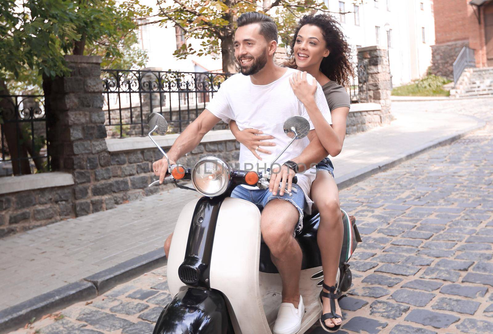 Cheerful young couple riding a scooter and having fun by asdf