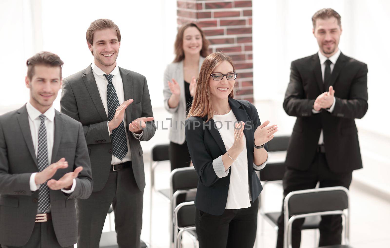 Row of confident delegates applauding to speaker after successful presentation at conference