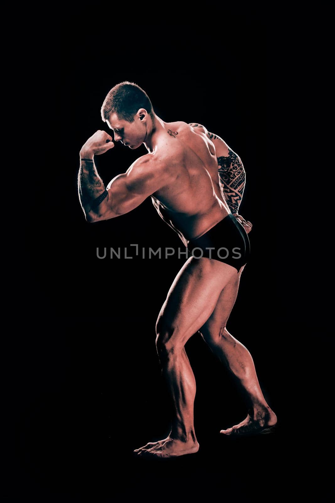 in full growth. handsome bodybuilder guy showing his biceps.isolated on black background