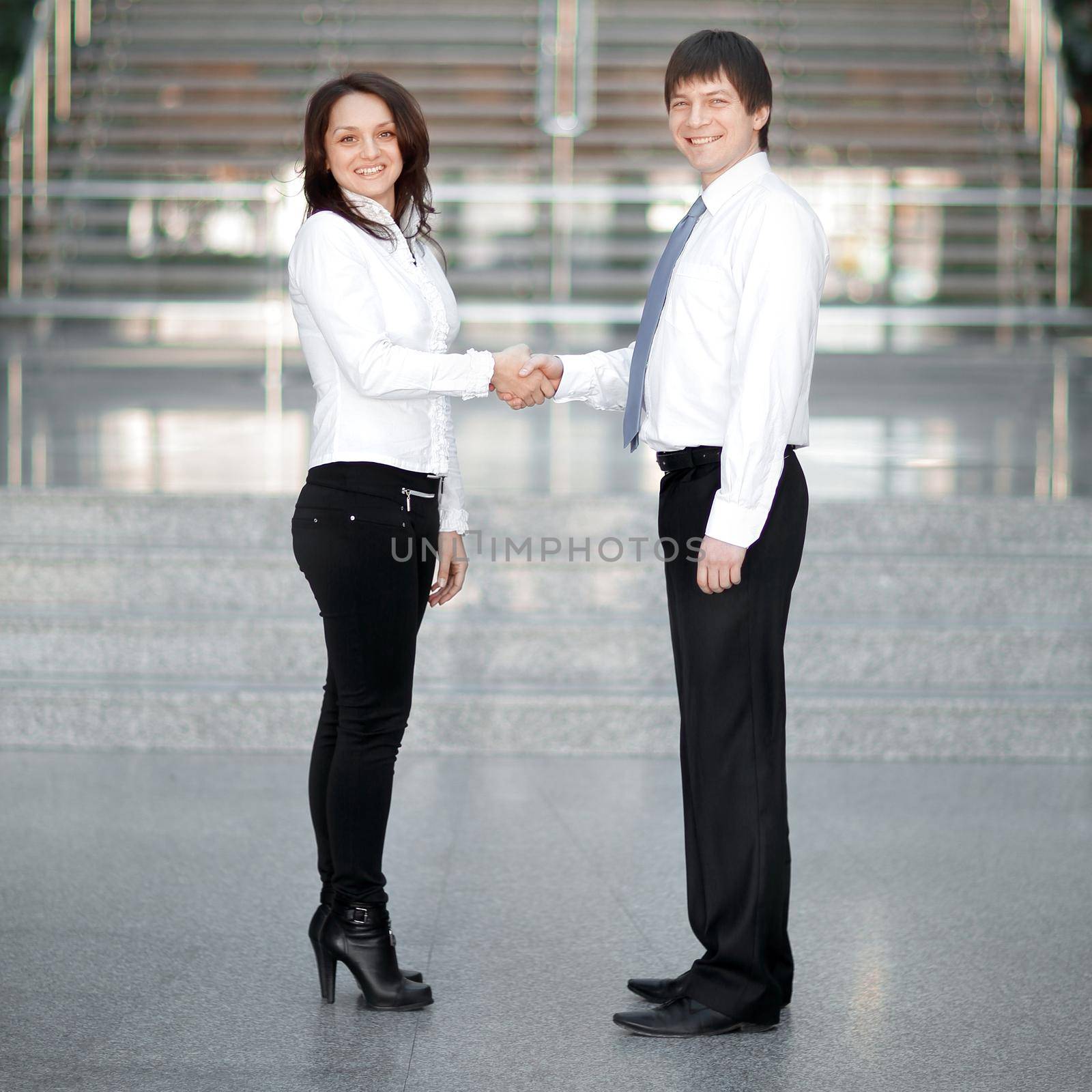 welcome handshake of young business partners on the background of the office. by SmartPhotoLab