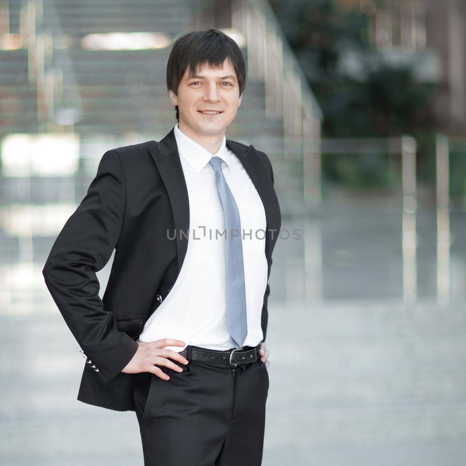 portrait of confident businessman on background of a blurred office. by SmartPhotoLab