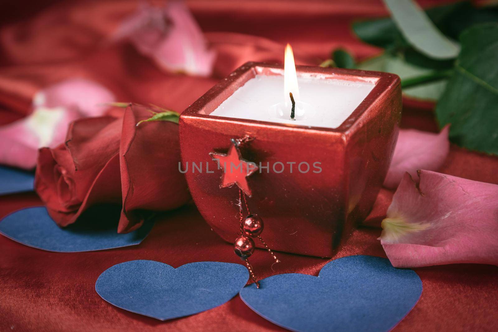 candle and rose on red silk background. photo with copy space