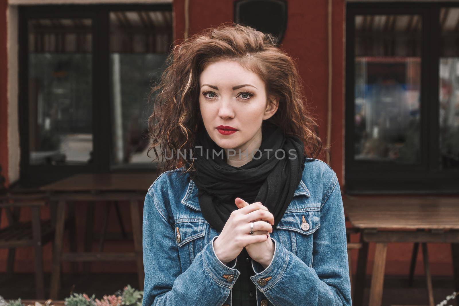 beautiful young woman in denim jacket standing near street cafe