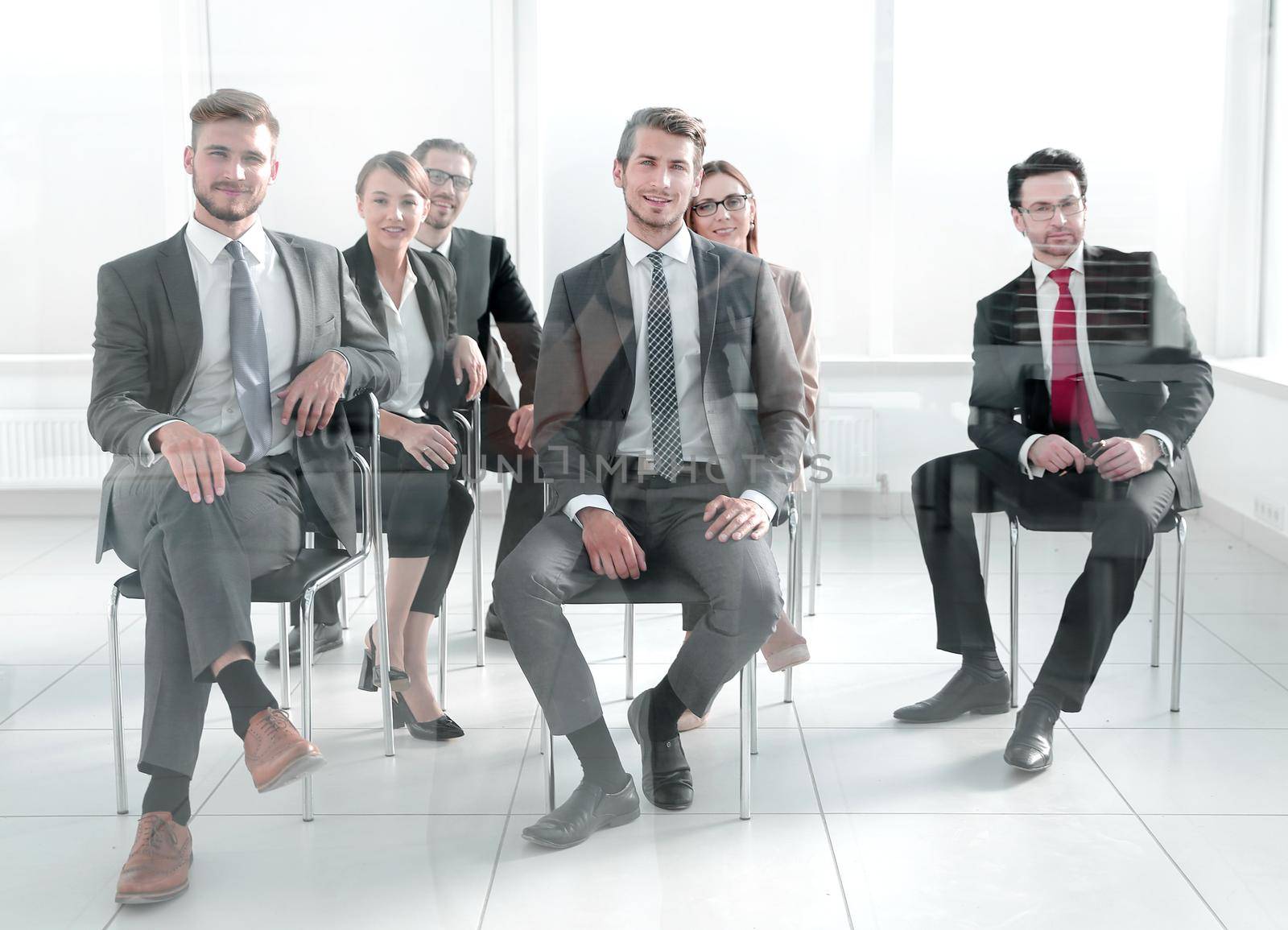 Man and women sitting on chairs in row by asdf