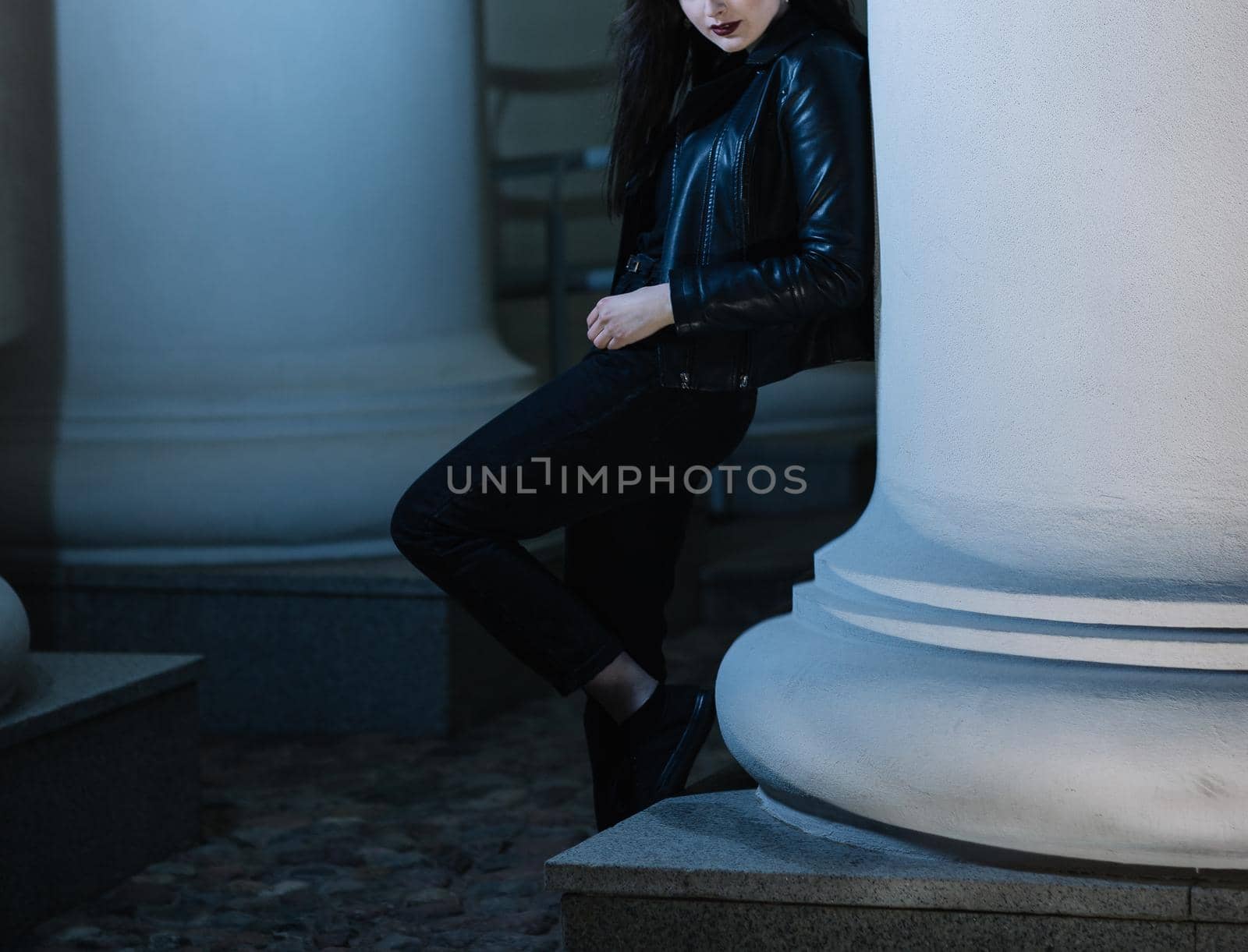 stylish young woman standing near a pillar of a city building . city life