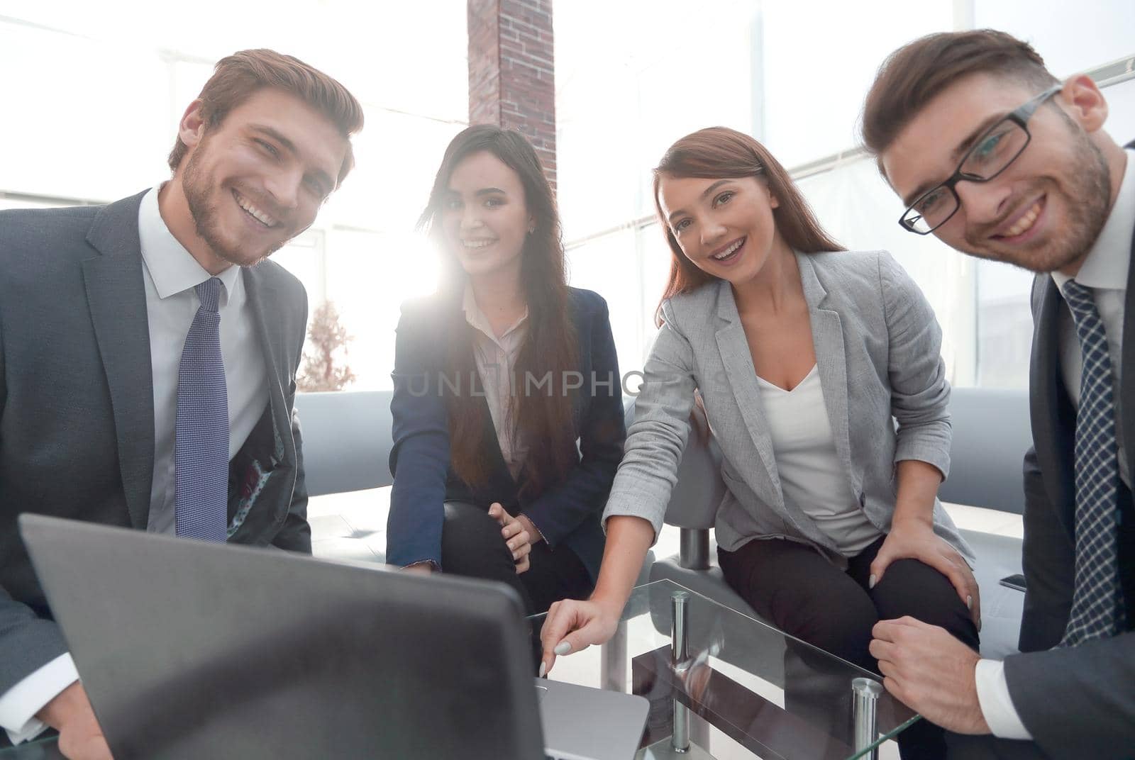 Happy creative business team gathered around a laptop at office.