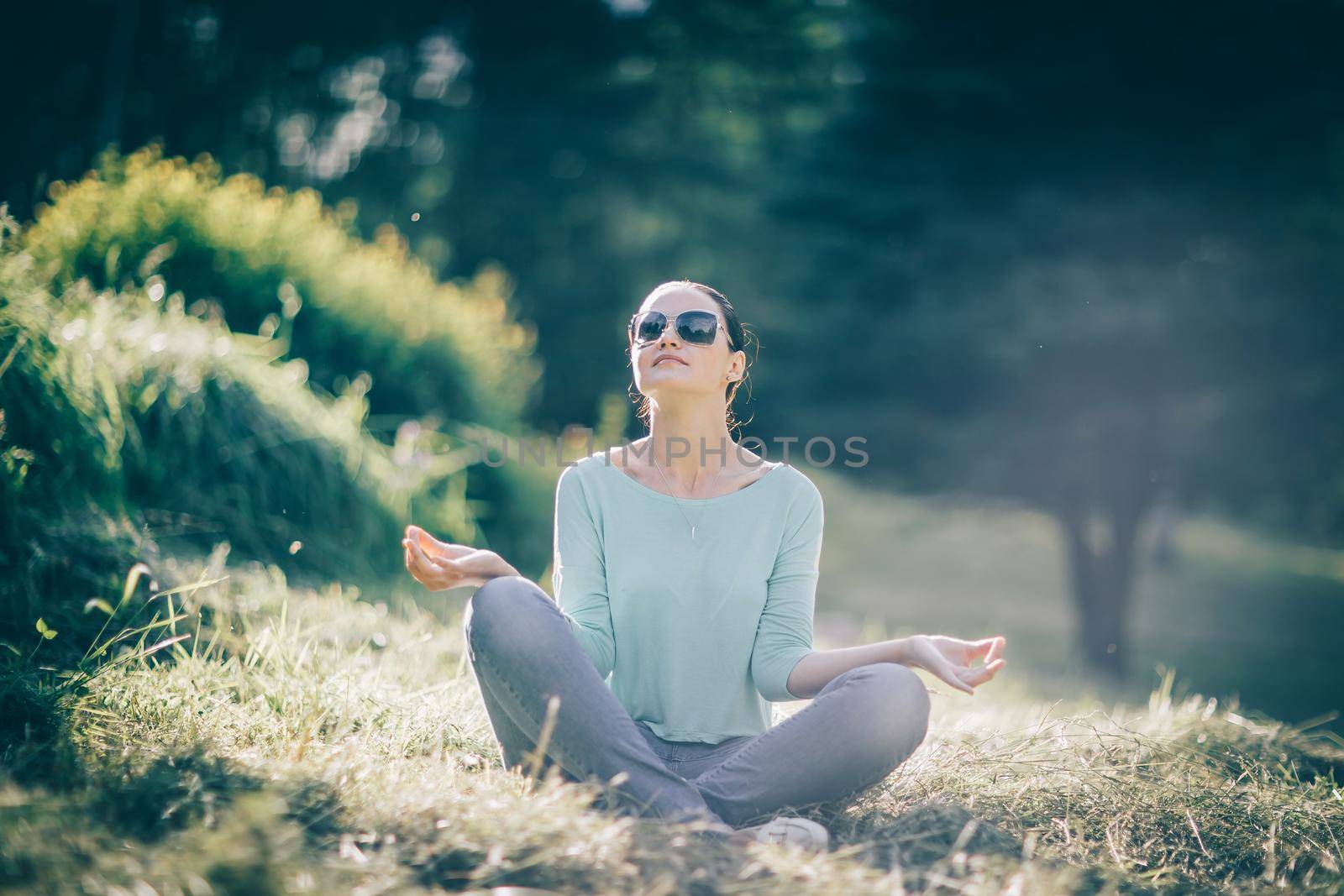 young woman sitting in Lotus position in Park by SmartPhotoLab