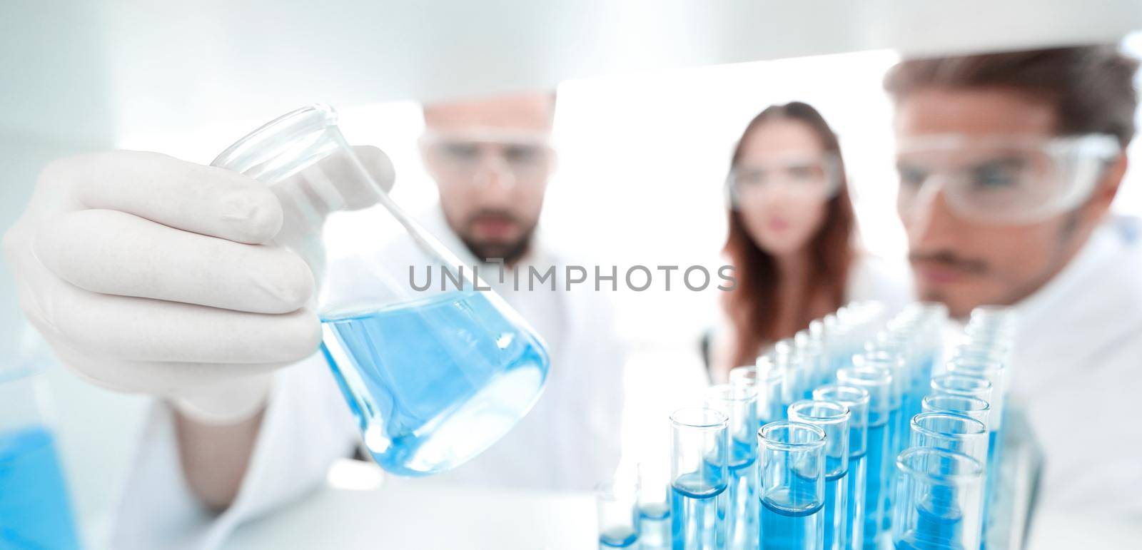 closeup.a group of scientists studying the liquid in the glass tube by asdf