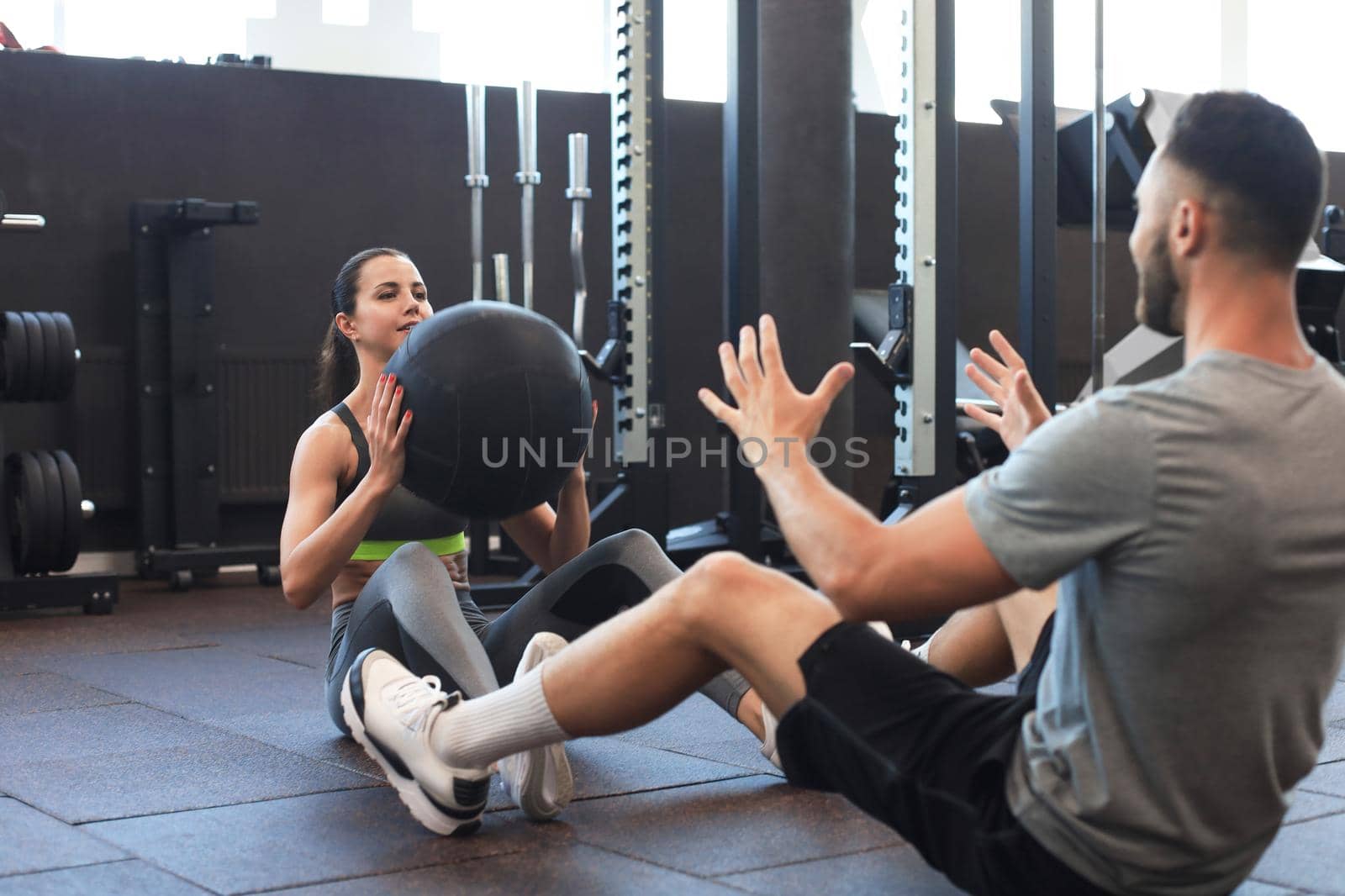 Beautiful young sports couple is working out with medicine ball in gym