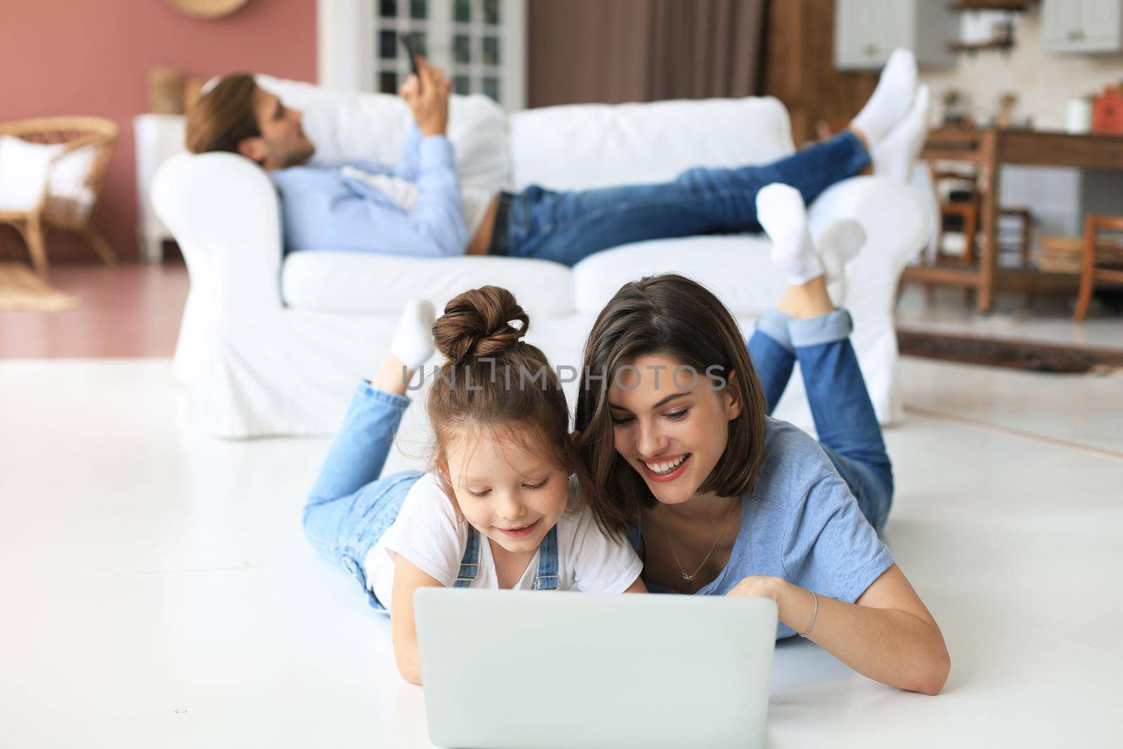 Happy mom and little child girl looking at screen laptop, talking to webcam, chatting online via computer app