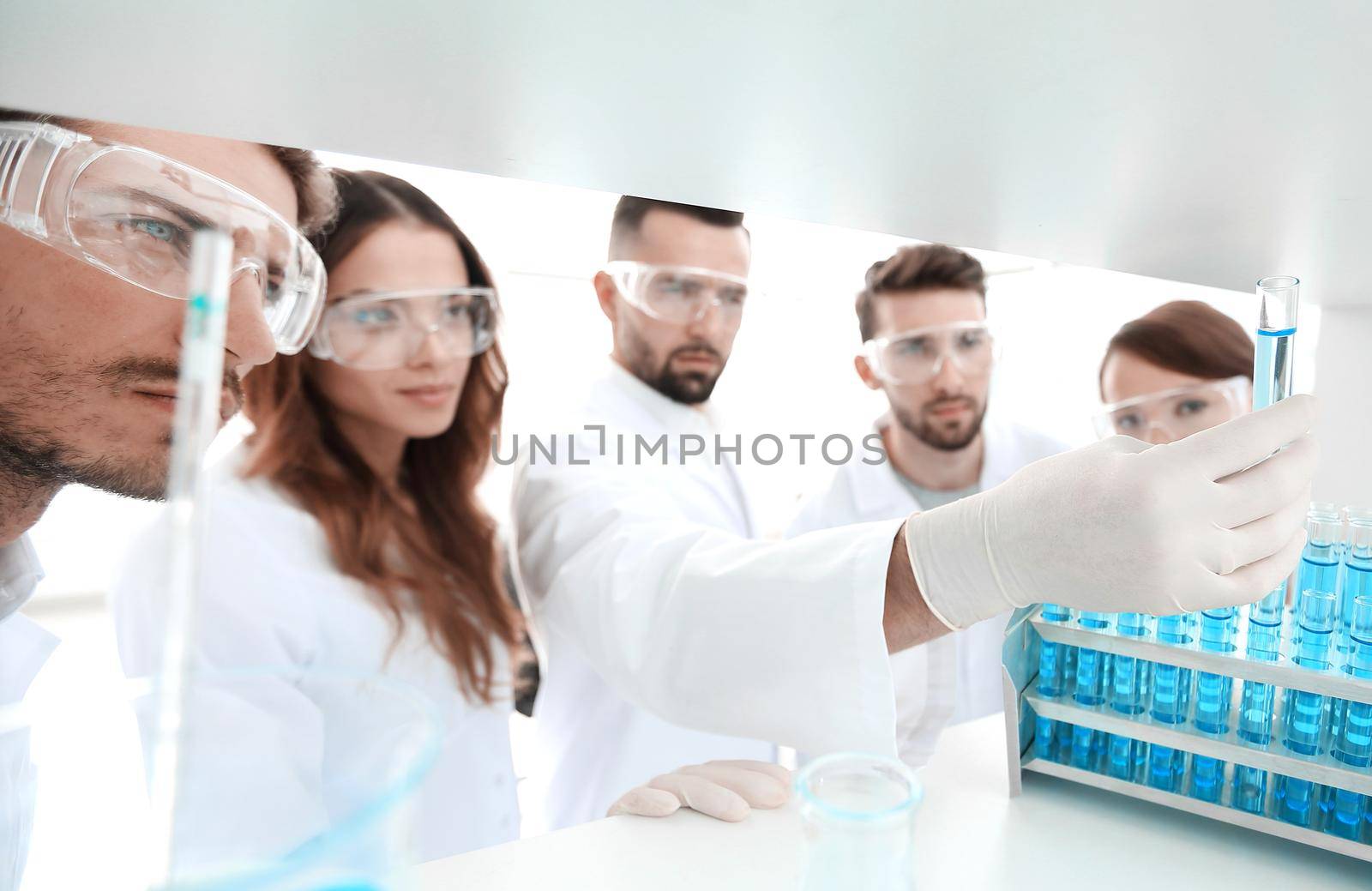group of microbiologists studying the liquid in the glass tube. the concept of the research