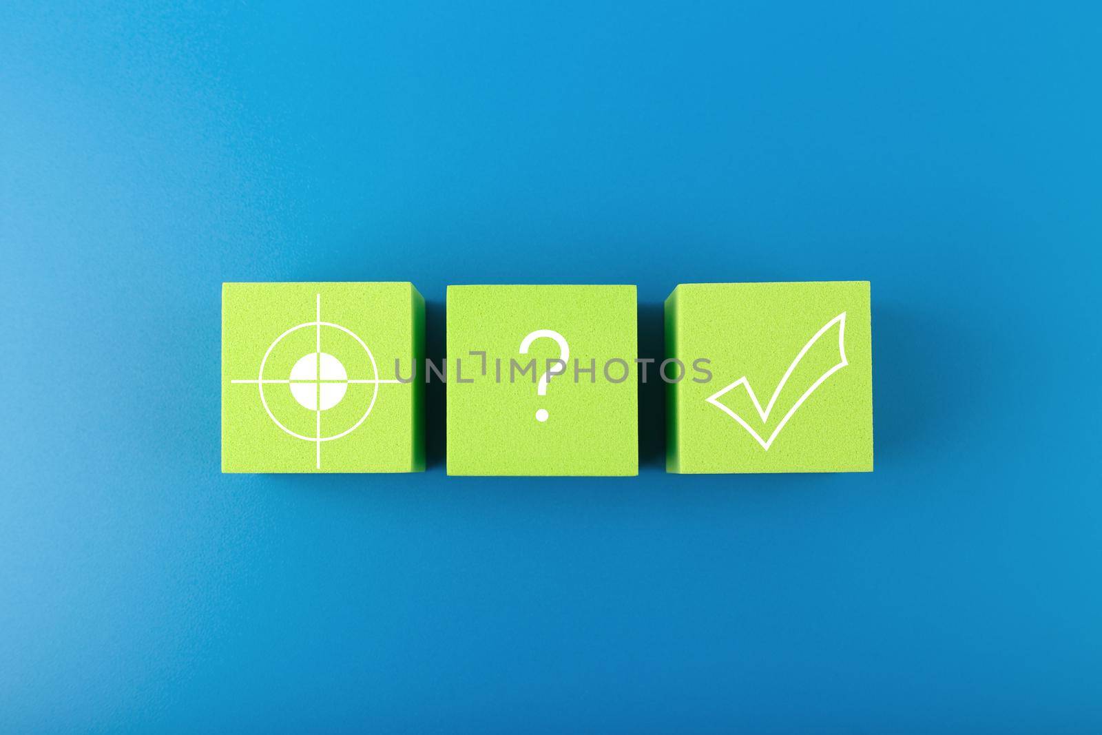 Target, question sign and checkmark on green toy cubes on dark blue background Concept of goal, success, reaching business and personal aims