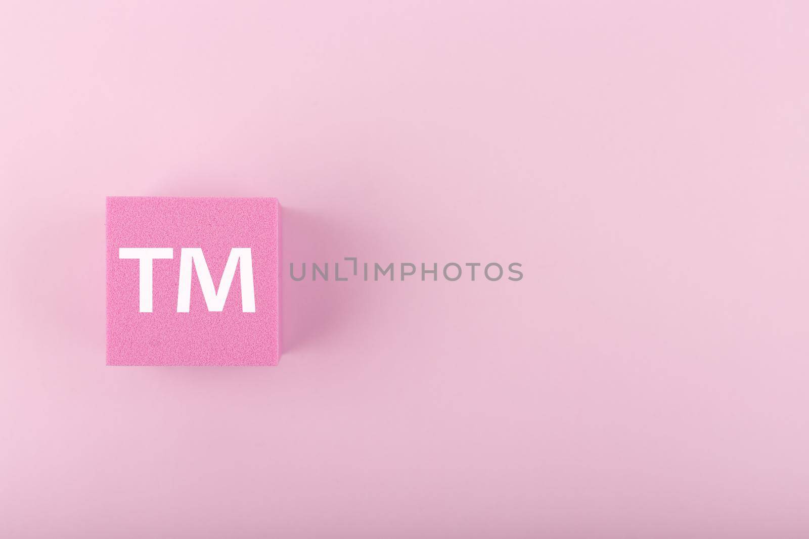 White TM trademark sign on pink figure on pink background with copy space. Minimal trendy concept of intellectual property registration and protection