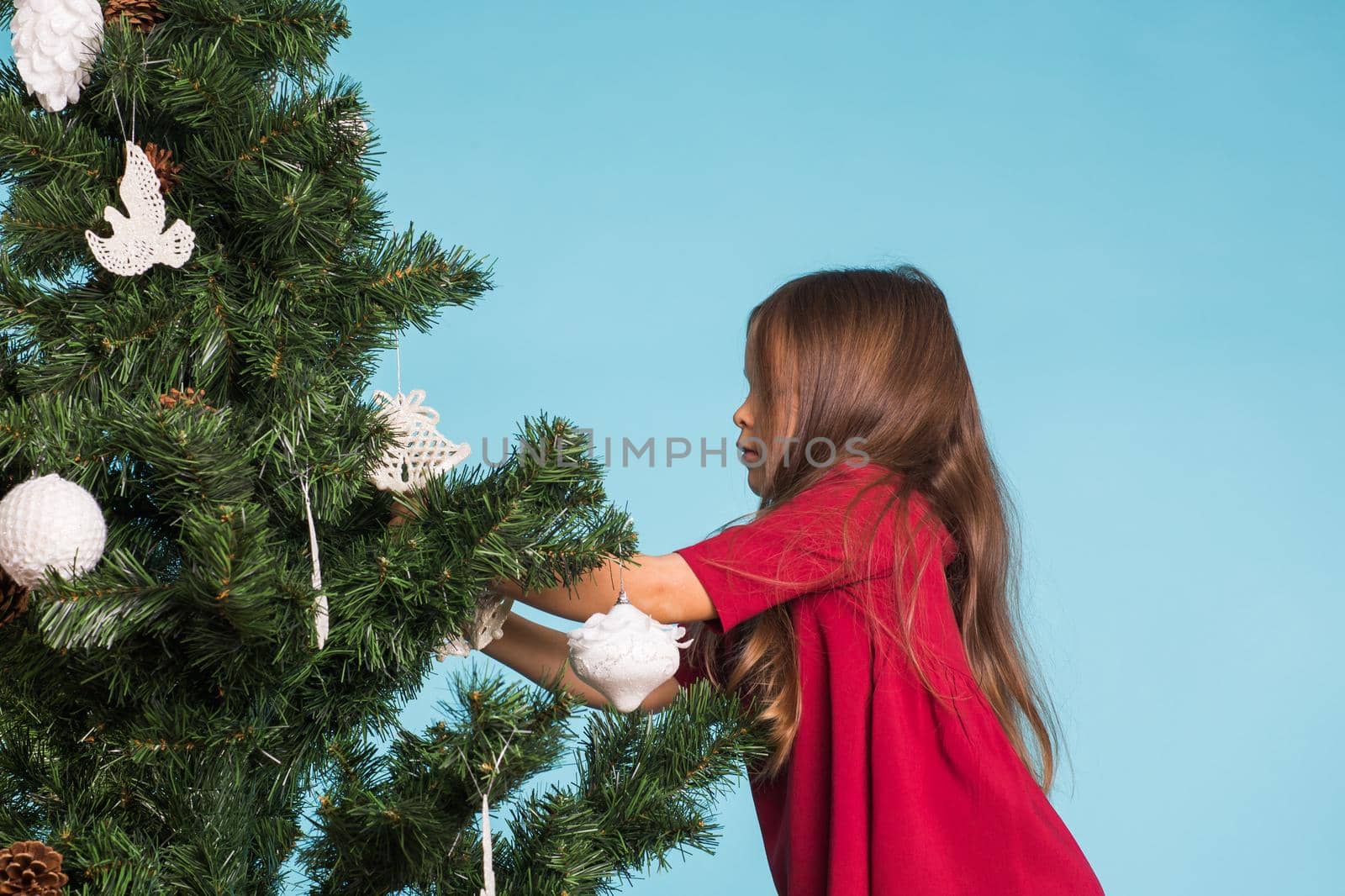 Christmas, childhood and people concept - little girl decorating the christmas tree.