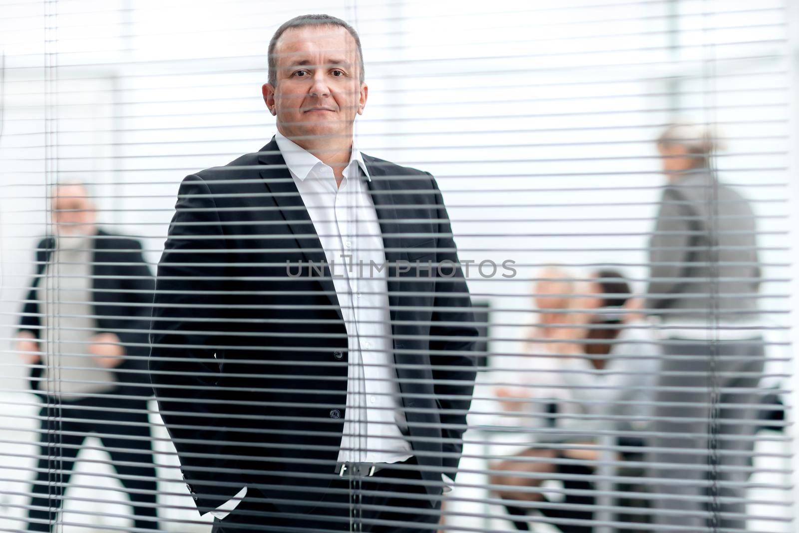 through the blinds. successful business man standing in modern office. business people