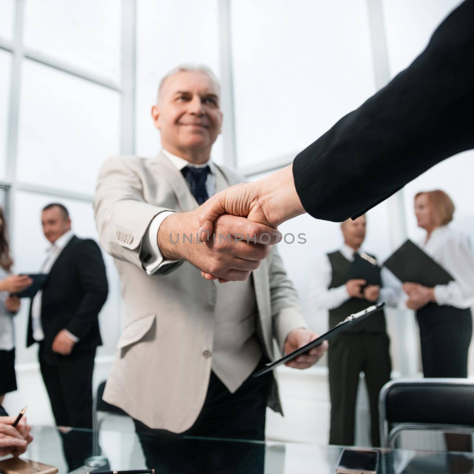 businessman confidently shaking hands with his business partner. by SmartPhotoLab