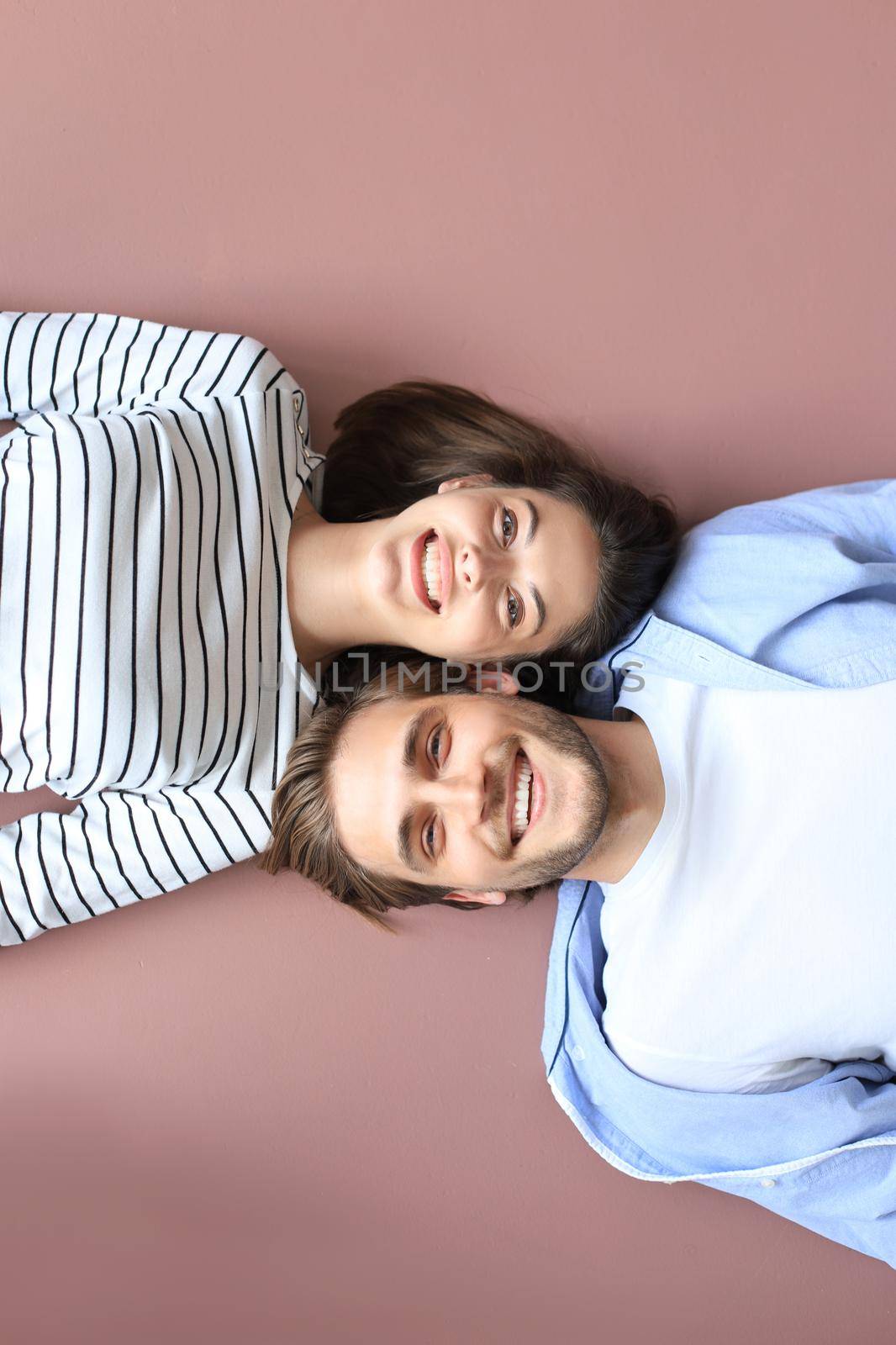 Top view portrait of smiling young couple lying relaxing on warm floor at home, happy family relaxing at home. by tsyhun