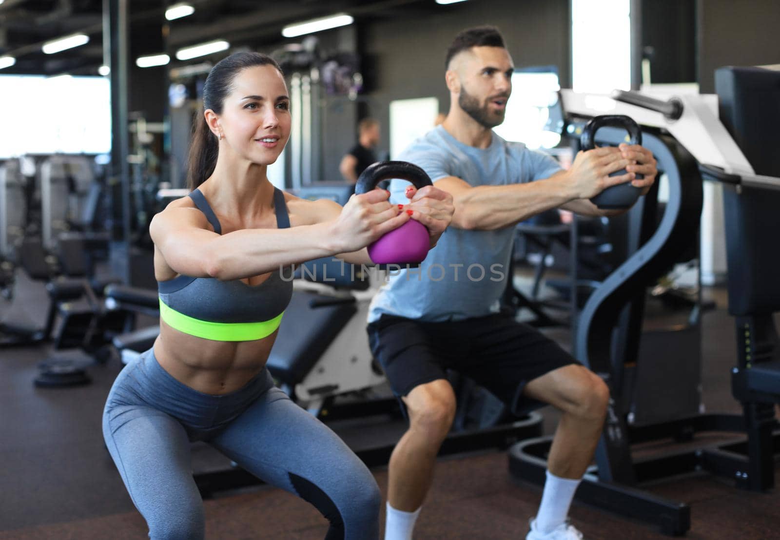 Fit and muscular couple focused on lifting a dumbbell during an exercise class in a gym
