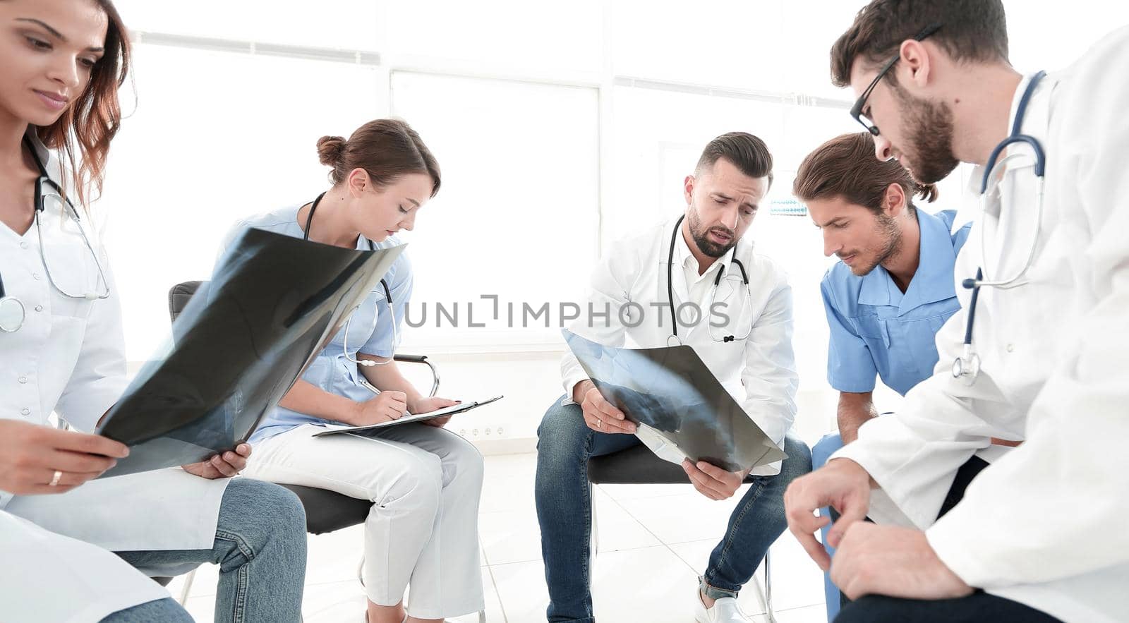 radiologists and a surgeon discussing a radiograph of a patient sitting in the office.