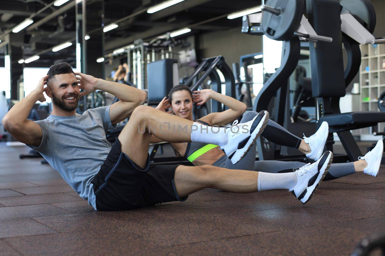 Attractive man and woman working in pairs performing sit ups in gym