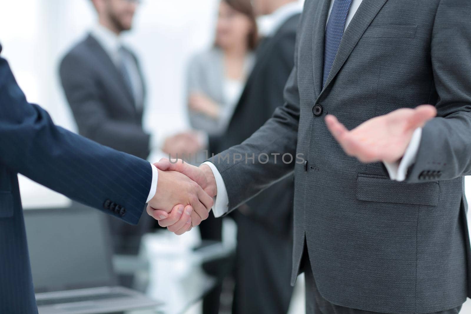 Business partners handshaking over business objects on workplace by asdf