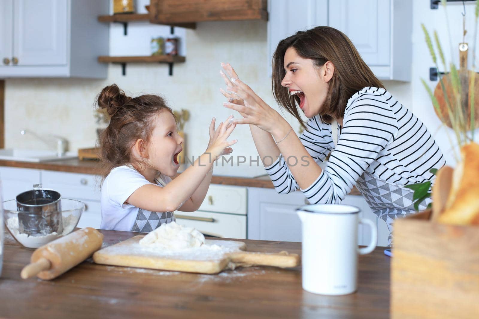 Playful little girl cooking at kitchen with her loving mother