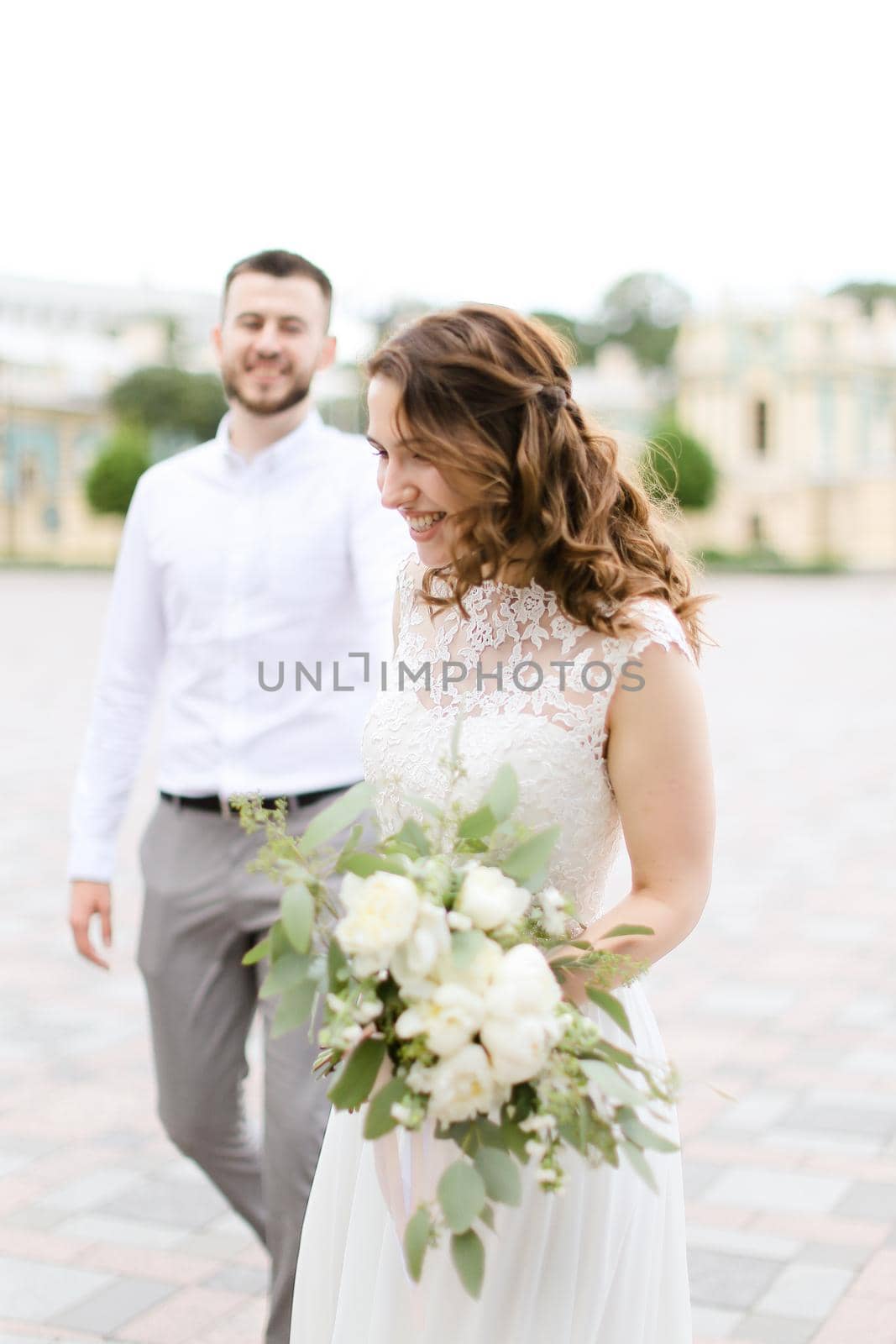 Caucasian bride walking with handsome groom bouquet of flowers in city. by sisterspro