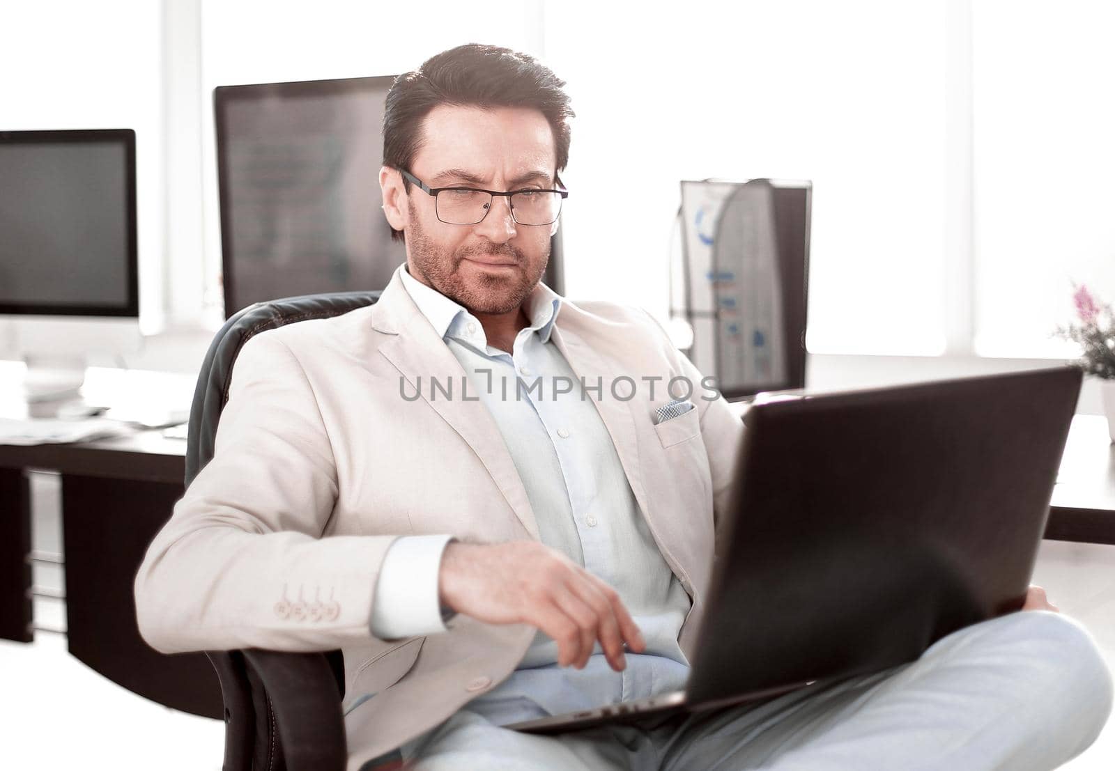 businessman using a laptop sitting at his Desk by asdf