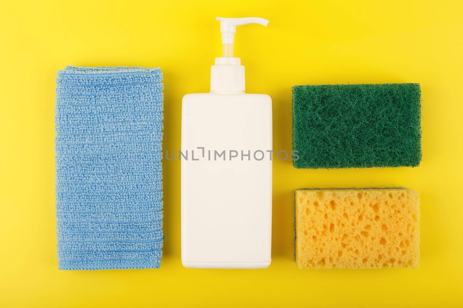 Top view of detergent, dust cloth, cleaning sponge and abrasive sponge on yellow background by Senorina_Irina