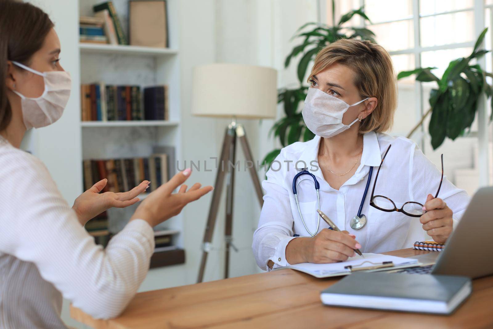 Middle aged female doctor therapist in consultation with patient in office