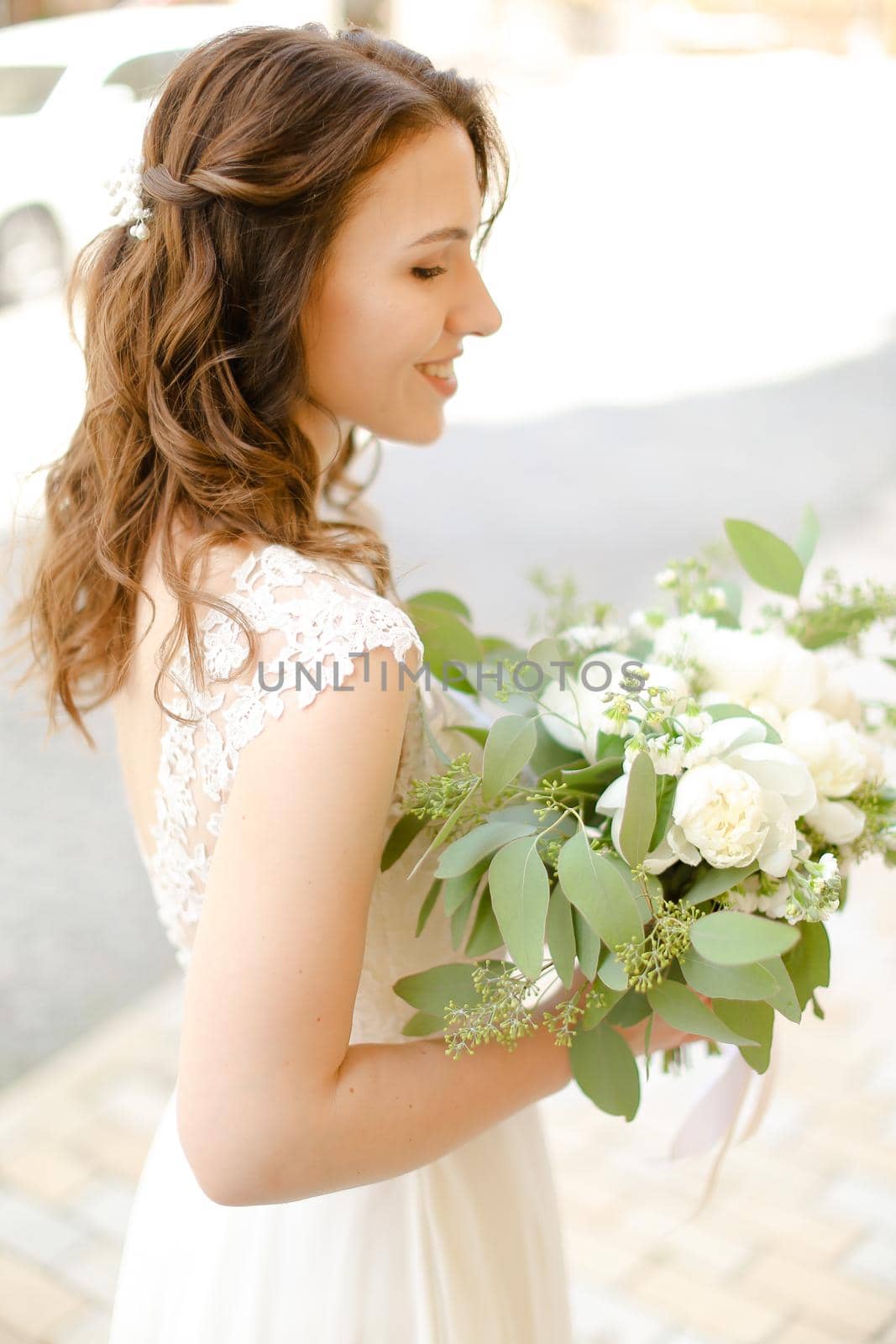 Happy cute bride keeping bouquet of flowers and wearing white dress. by sisterspro