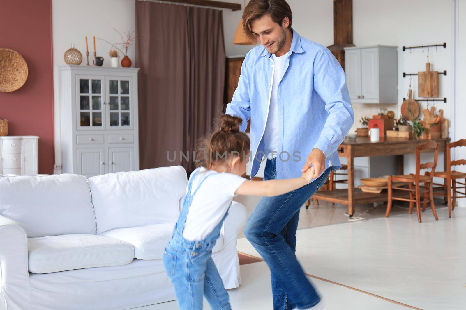 Handsome young man dancing at home with his little cute daugther