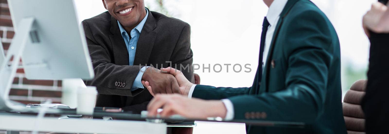 handshake international business partners on a Desk by SmartPhotoLab