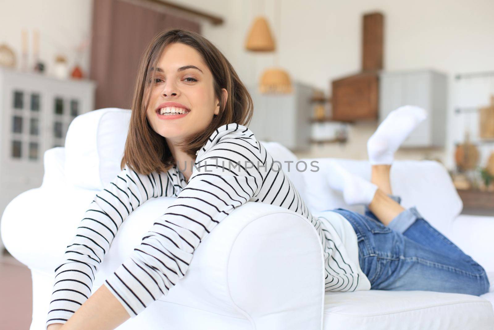 Smiling beautiful woman lying on a sofa in living room at home