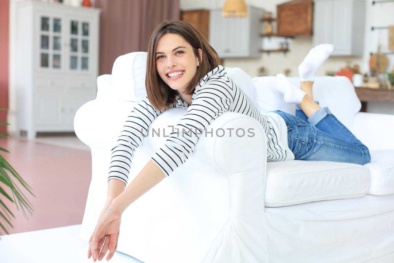 Smiling beautiful woman lying on a sofa in living room at home