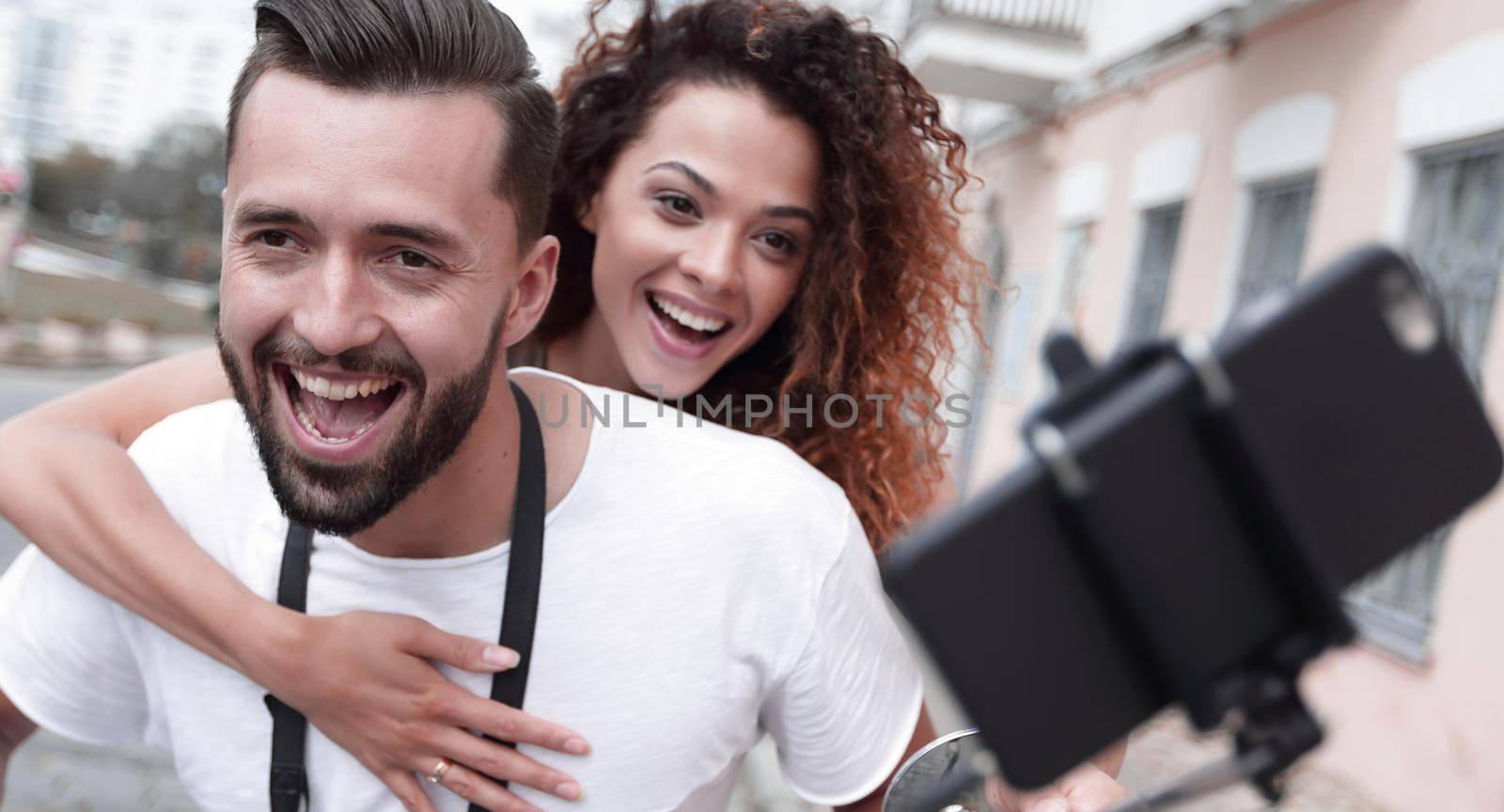 Happy couple on scooter making selfie photo on smartphone outdoor