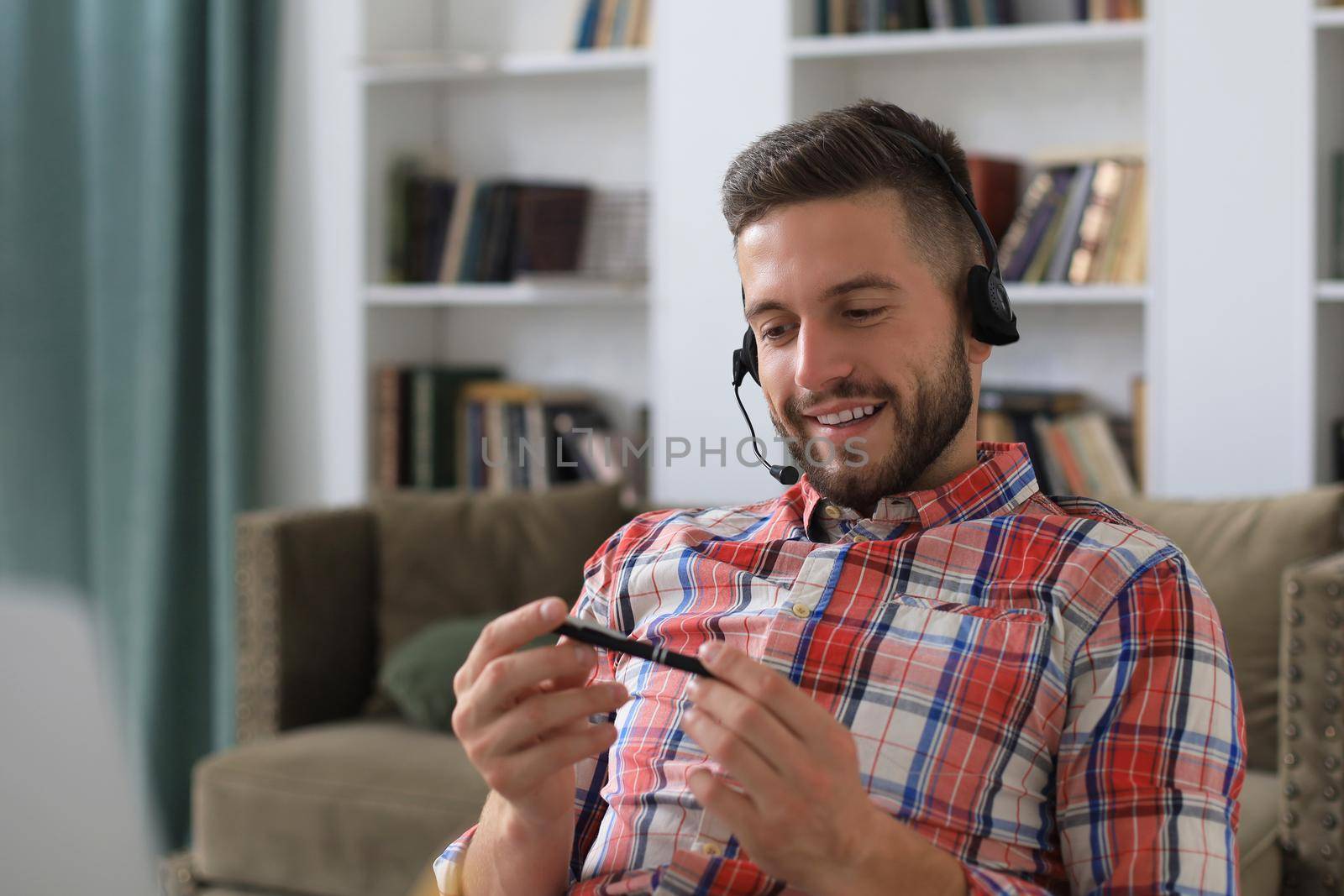 Happy young man in earphones working on laptop from home during self isolation