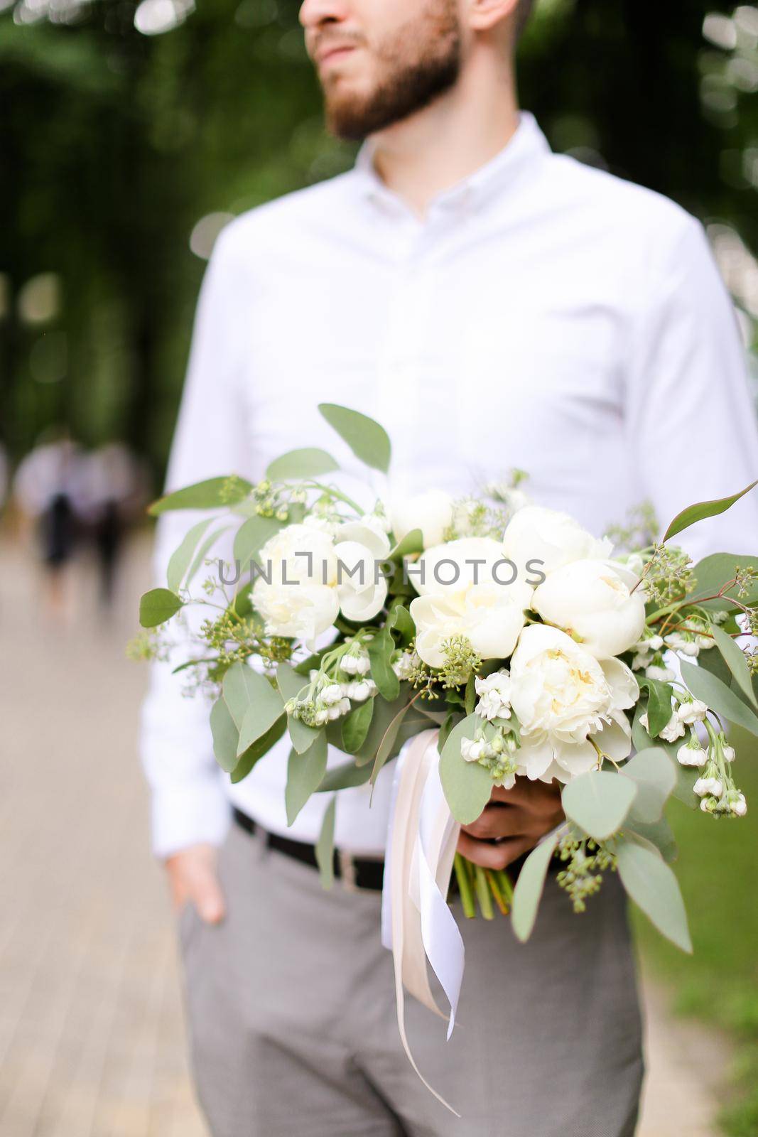 Caucasian happy groom waiting for bride with bouquet of flowers. by sisterspro