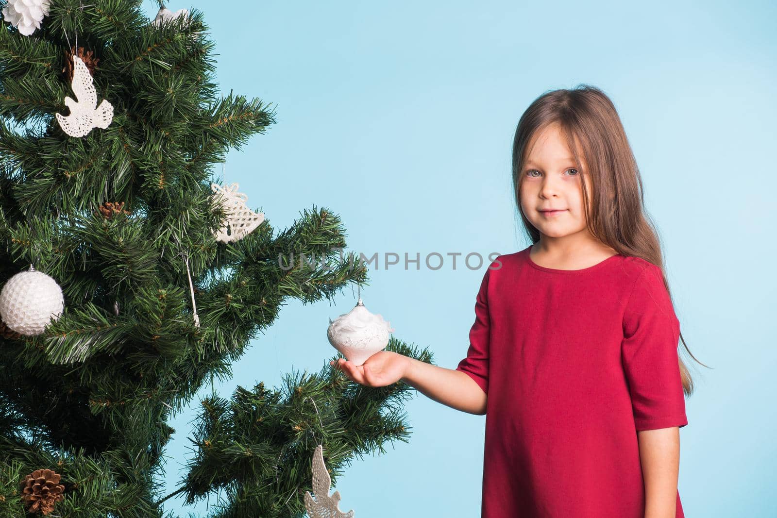 Little girl with christmas tree on blue background.