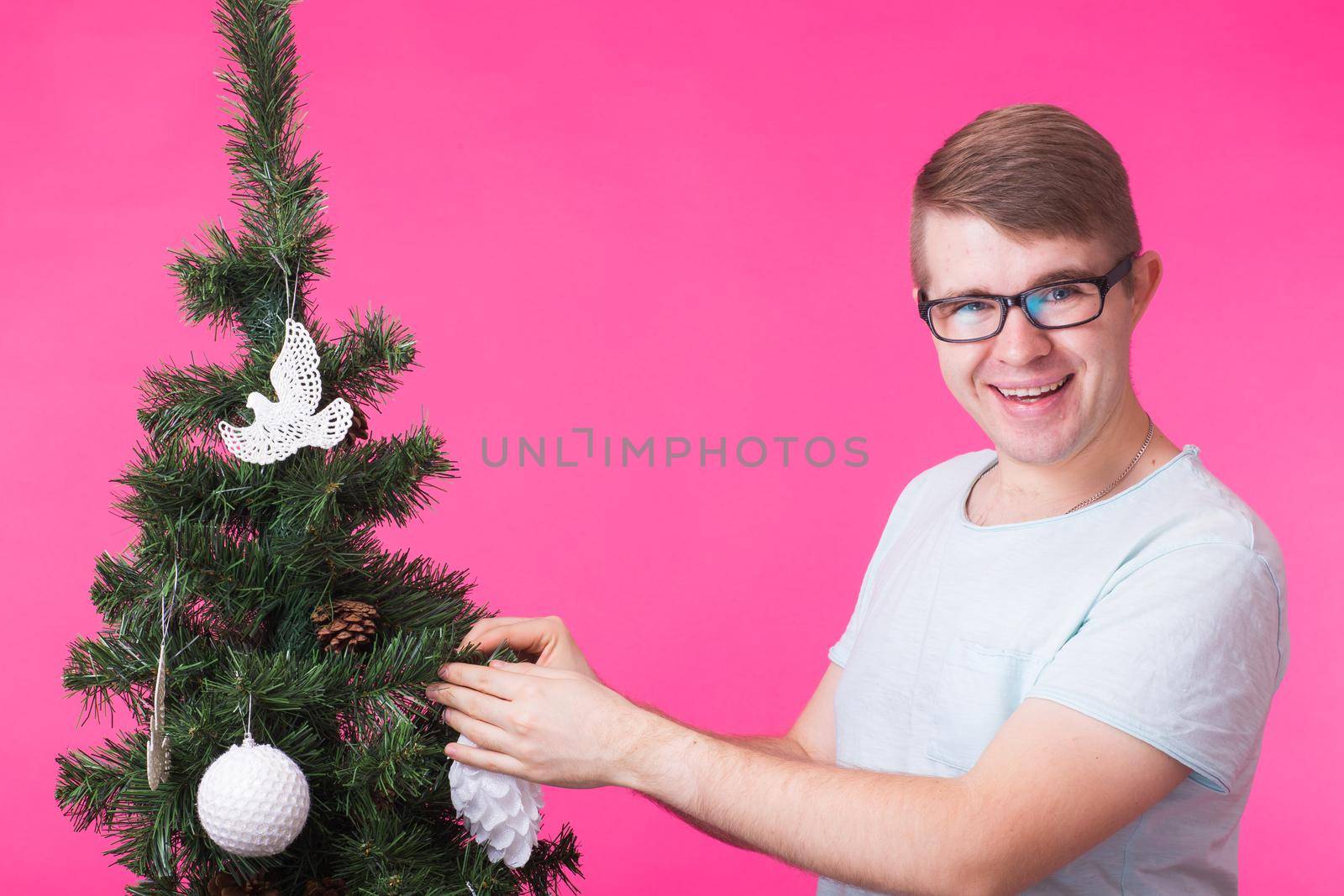 Christmas and holiday concept - Portrait of smiling man with Christmas Tree on pink background.