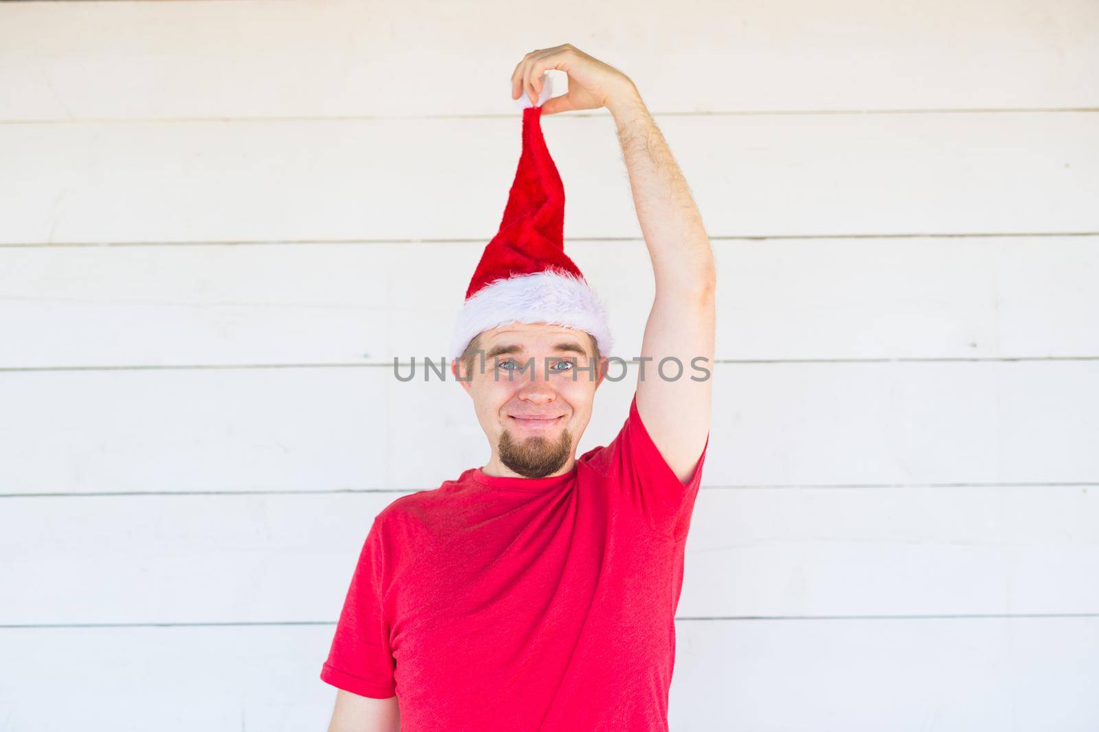people, christmas ans clothing concept - young man in santa costume posing on white background.