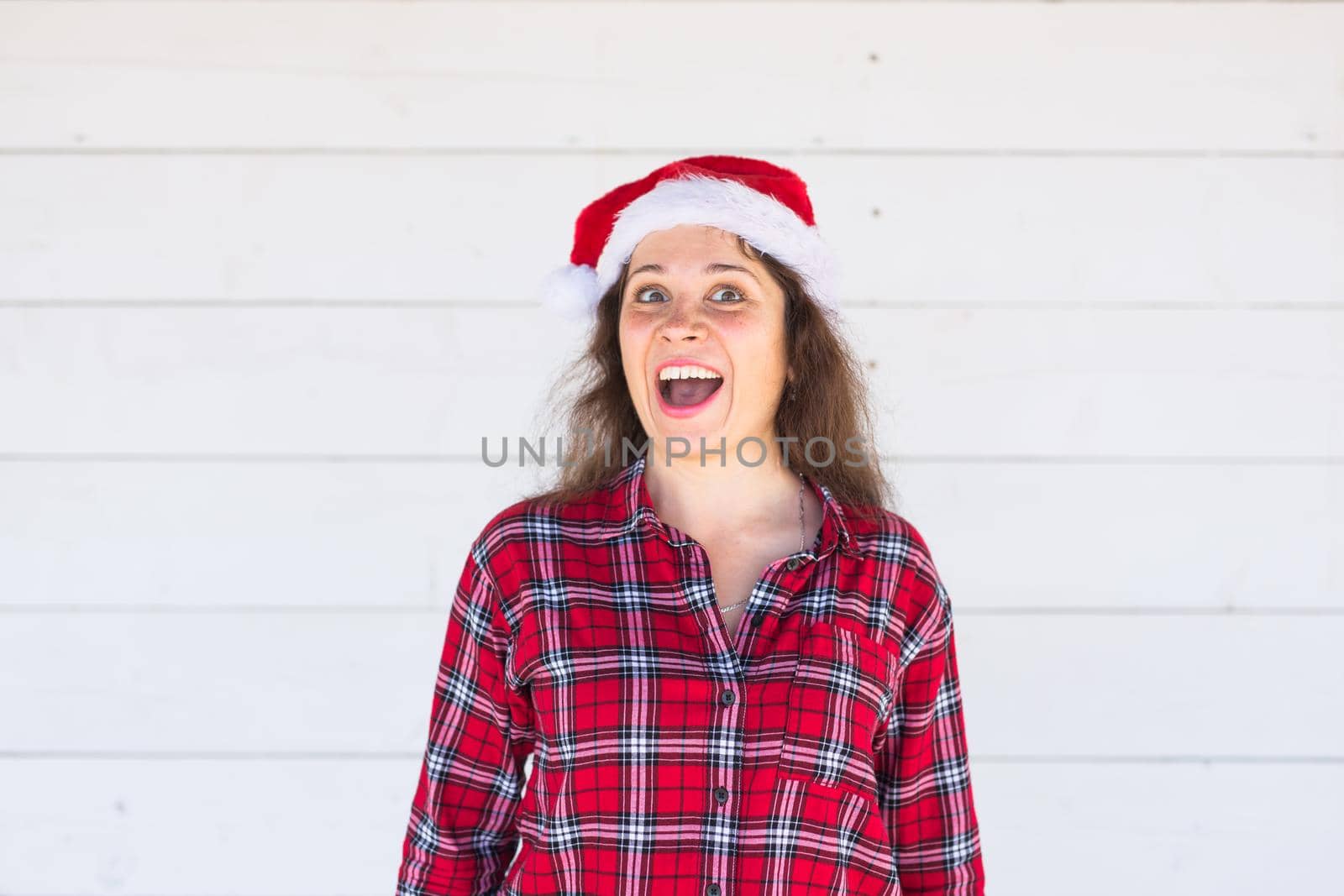 Christmas, holidays, people concept - young woman in santa hat and shirt smiling over the white background by Satura86