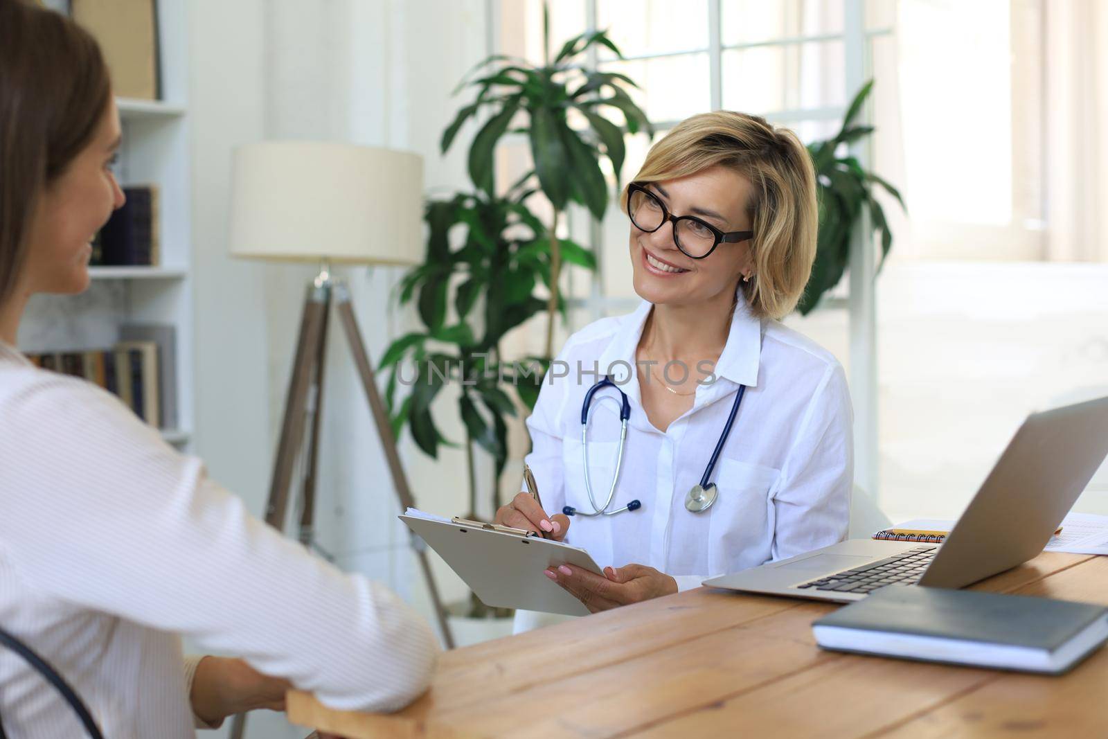 Middle aged female doctor therapist in consultation with patient in office